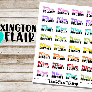 May include: A sheet of colorful stickers with the text "Clean Brushes" repeated multiple times. The stickers are arranged in a grid pattern and are printed on a white background. The text "Lexington Flair" appears at the top and bottom of the sheet.