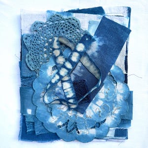 May include: A layered textile collage featuring various shades of blue fabric scraps, including a circular crocheted doily, a tie-dyed ribbon with a repeating circular pattern, and rectangular pieces of indigo-dyed cotton with frayed edges.