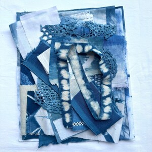 May include: A collection of assorted fabric scraps in various shades of blue and white. The bundle includes pieces of dyed linen, cotton, and lace, featuring shibori-style patterns, solid indigo tones, and textured crochet elements layered together.