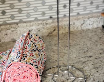 May include: A silver metal paper towel holder with a roll of colorful patterned kitchen towels on a countertop.