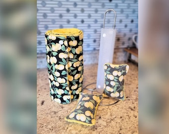 May include: A set of three reusable kitchen towels with a lemon print. The towels are black with yellow lemons and green leaves. The towels are rolled up and placed on a counter top.