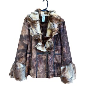 May include: A brown faux fur coat with a floral pattern. The coat has a fur collar and cuffs, and is hanging on a black hanger. The coat has a single button closure and black trim.