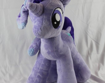 May include: A plush purple unicorn toy with a blue and purple mane and tail. The unicorn has a white horn and large, black eyes.