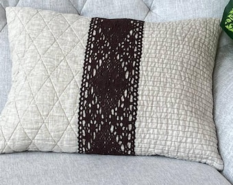May include: A rectangular throw pillow featuring a beige quilted fabric on the left side, a dark brown vertical lace panel in the center with a diamond pattern, and a beige textured fabric with horizontal stitching on the right side.