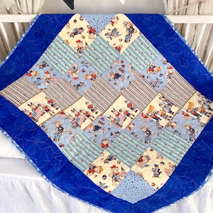 Puede incluir: Una colcha para bebé azul y blanca con un tema patriótico. La colcha está hecha de varias telas con diferentes patrones, incluyendo estrellas, rayas y corazones. La colcha presenta un patrón repetitivo de osos de peluche que llevan ropa roja, blanca y azul.