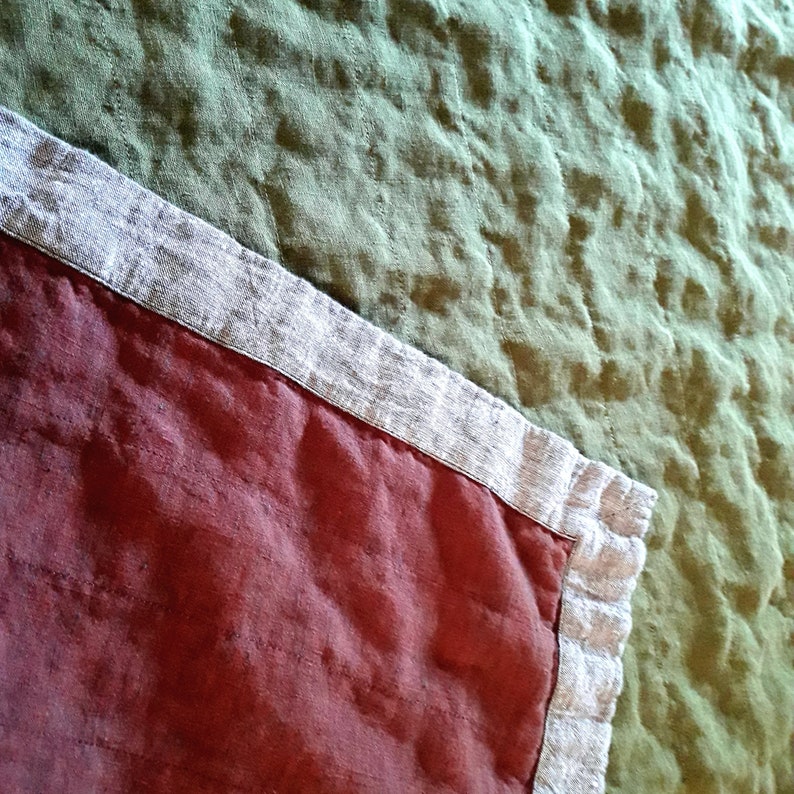 Puede incluir: Primer plano de un textil acolchado con una secci&oacute;n burdeos y una secci&oacute;n verde salvia. La secci&oacute;n burdeos tiene un borde de color beige claro. La secci&oacute;n verde salvia tiene un aspecto texturizado. El textil es probablemente un edred&oacute;n o una manta.