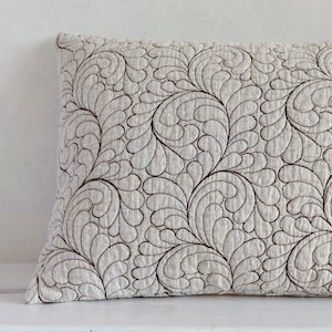 May include: A beige throw pillow with a brown swirl pattern. The pillow is made of a soft, textured fabric.
