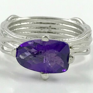 May include: A silver ring with a purple amethyst gemstone set in a twisted wire design.