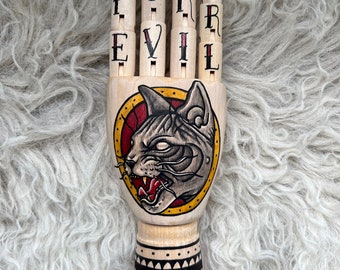 Wooden hand with a sphynx and flowers tattoo design