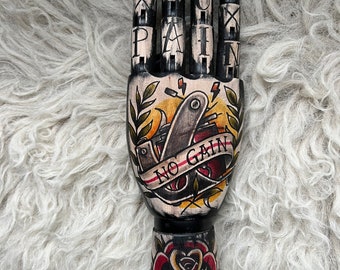 Black wooden hand with a tattoo machine and rose tattoo design