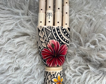 Wooden hand with flowers and a Polynesian tattoo design