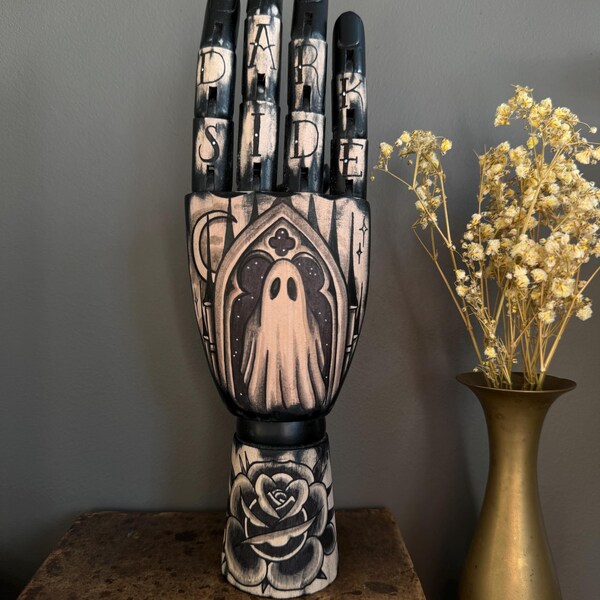 Mano di legno nera con tatuaggio raffigurante un fantasma e una finestra di una chiesa