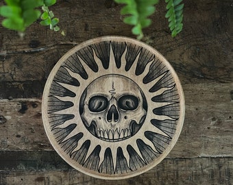 Wooden plate with an original drawing of a sun with skull