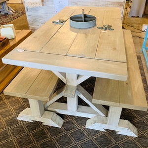 May include: A light gray wooden picnic table with attached benches. The table has a rectangular top and a sturdy base with angled supports. The benches are the same color as the table. The table is approximately 72 inches long.