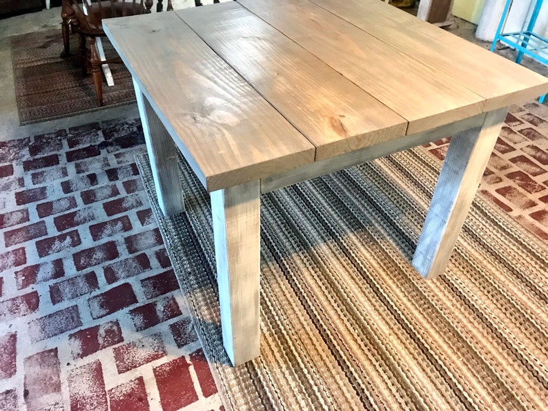 May include: A light gray wooden table with a distressed finish. The table has a rectangular top and four legs. The table is sitting on a striped rug.
