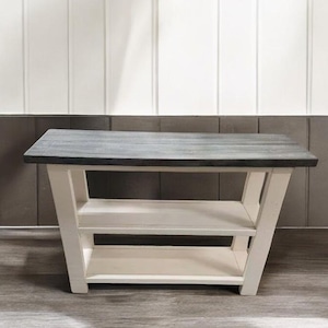 May include: A rectangular console table featuring a dark charcoal gray wooden top and a white painted base. The structure includes two open shelves positioned between four angled legs that flare outward toward the base, providing storage space.