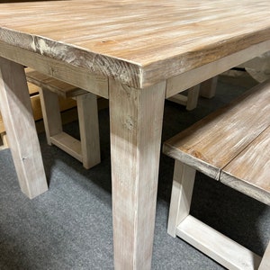 K&ouml;nnte beinhalten: Ein wei&szlig; gestrichener Holz-Esstisch mit zwei passenden B&auml;nken. Tisch und B&auml;nke haben einen rustikalen, l&auml;ndlichen Stil.