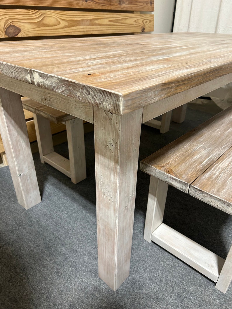 K&ouml;nnte beinhalten: Ein wei&szlig; gestrichener Holz-Esstisch mit zwei passenden B&auml;nken. Tisch und B&auml;nke haben einen rustikalen, l&auml;ndlichen Stil.