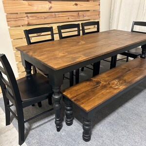 May include: A rectangular dining table with a dark brown stained wood top and black painted legs, accompanied by four black wooden chairs with horizontal back slats and a matching long wooden bench with black turned legs.