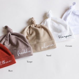 Peut inclure: Cinq bonnets de b&eacute;b&eacute; nou&eacute;s de couleurs diff&eacute;rentes avec des noms personnalis&eacute;s brod&eacute;s. Les couleurs sont rouille, taupe, sable, cr&egrave;me et blanc. Les noms sont Ethan, Freddie, Olivia, Harper et Hudson.