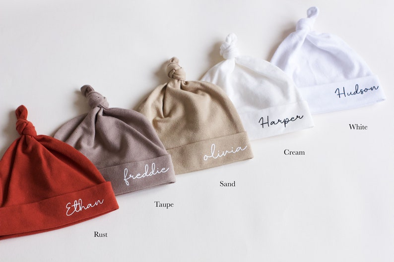 Peut inclure: Cinq bonnets de b&eacute;b&eacute; nou&eacute;s de couleurs diff&eacute;rentes avec des noms personnalis&eacute;s brod&eacute;s. Les couleurs sont rouille, taupe, sable, cr&egrave;me et blanc. Les noms sont Ethan, Freddie, Olivia, Harper et Hudson.
