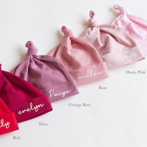 Peut inclure: Six bonnets pour b&eacute;b&eacute;s de couleurs diff&eacute;rentes avec des n&oelig;uds sur le dessus. Les bonnets sont &eacute;tiquet&eacute;s avec les noms "Molly", "Evelyn", "Paige", "Willow", "Robyn" et "Candyfloss". Les couleurs des bonnets sont rouge, vin, rose vintage, rose, rose fonc&eacute; et barbe &agrave; papa.