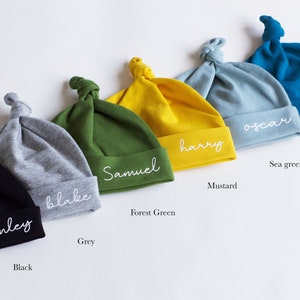 Peut inclure: Six bonnets pour b&eacute;b&eacute; personnalis&eacute;s dans diff&eacute;rentes couleurs, notamment noir, gris, vert for&ecirc;t, moutarde, vert d'eau et sarcelle. Chaque bonnet porte un nom diff&eacute;rent brod&eacute; : Finley, Blake, Samuel, Harry, Oscar et Jude.