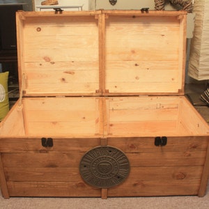 wooden trunk with the lid open, lid is being held open by two rope lion stays.