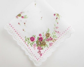 May include: White cotton handkerchief with a floral design featuring pink and brown roses and green leaves. The handkerchief has a scalloped edge with a dotted pattern.