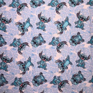 Pu&ograve; includere: Un tessuto bianco con un motivo ripetuto di personaggi Stitch blu dal film Disney Lilo & Stitch. I personaggi sono in varie pose e sono contornati di nero.