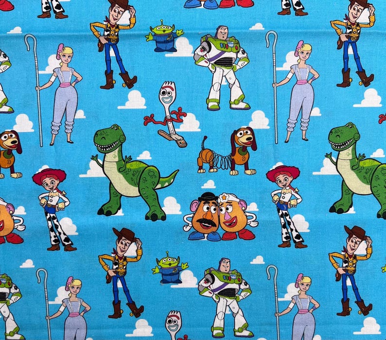 Op de afbeelding: Een herhalend patroon van Toy Story-personages op een lichtblauwe achtergrond. Het ontwerp bevat Woody, Buzz Lightyear, Jessie, Rex en andere personages uit de animatiefilm, met witte wolkenaccenten.