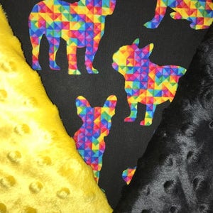 May include: Black fabric with a rainbow geometric pattern featuring silhouettes of French Bulldogs. The fabric is paired with a yellow and a black fuzzy fabric.