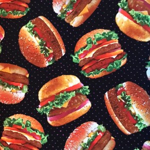 May include: A repeating pattern of illustrated hamburgers on a black background with small purple dots. The burgers have sesame seed buns, lettuce, tomato, cheese, and a burger patty.