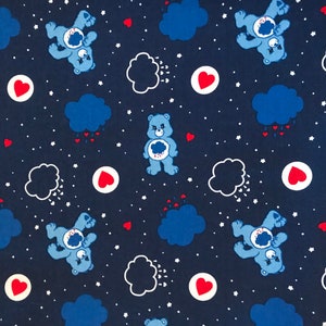 May include: A dark blue fabric featuring a repeating pattern of light blue bears with a cloud emblem on their chests. The design includes dark blue clouds raining small red hearts, solid red hearts inside white circles, and tiny white stars.