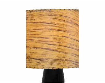 May include: A vintage lampshade with a woodgrain pattern in shades of brown and yellow. The lampshade has a stitched edge and is made of fabric.