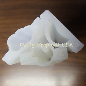Peut inclure: Plusieurs composants en plastique blanc sont empilés sur une surface marron. Les composants ont une forme incurvée avec une découpe et une section rectangulaire. Le texte "Daily Proposal USA" est visible.