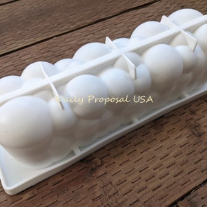 May include: A white silicone mould in the shape of clouds, suitable for baking or crafts. It features a rectangular base and a series of rounded, bubble-like shapes. The text "Daily Proposal USA" is visible.