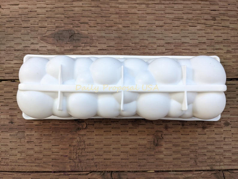 May include: A white plastic egg holder, rectangular with rounded compartments. The text "Daily Proposal USA" is printed on the side. Designed to hold a dozen eggs, it sits on a wooden surface. Ideal for storing eggs.