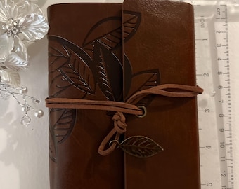Unique leather notebook with 80 natural brown pages for Travel can fit in biggish pocket. Really nice men’s gift. Has a filigree metal leaf