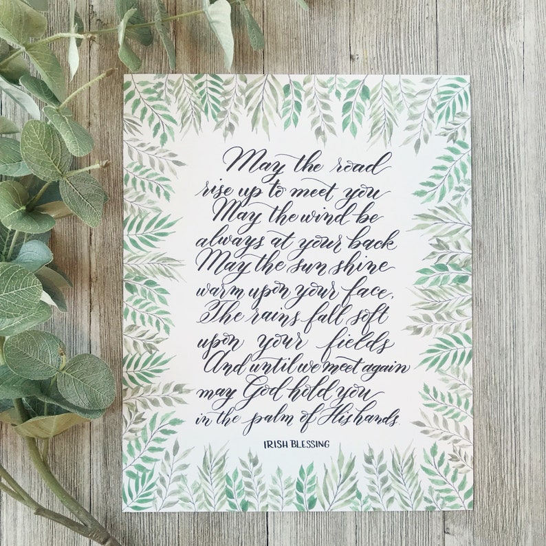May include: A rectangular print with an Irish blessing in elegant calligraphy. The text is surrounded by a border of green watercolor leaves. The background is white, and the text is in black. The words "Irish Blessing" are at the bottom.