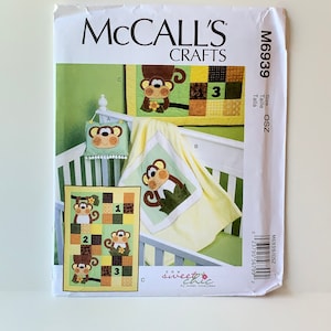 May include: A McCall's Crafts sewing pattern for a baby quilt and wall hanging featuring a monkey theme. The pattern is titled "Sew Sweet Chic" by Susan Cousineau. The pattern number is M6939.