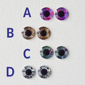 May include: Four sets of googly eyes, each with a different design. Set A is purple and pink with black pupils. Set B is brown and gold with black pupils. Set C is green and blue with black pupils. Set D is black and white with a spider web design.