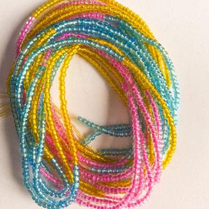 May include: A colorful beaded necklace with yellow, blue, and pink beads. The necklace is made of small, round beads that are strung together in a continuous loop.