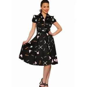 May include: A black dress with a white and pink print of hairdressing tools. The dress has a fitted bodice and a full skirt.