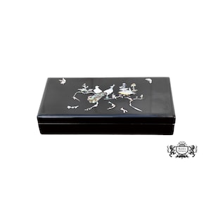 May include: A rectangular black lacquered box featuring an inlaid mother-of-pearl design on the lid. The intricate inlay depicts two birds perched on branches surrounded by floral elements, a small butterfly, and a crescent moon shape.