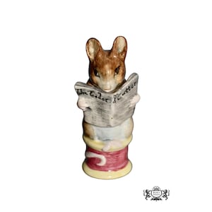 May include: A ceramic figurine of a mouse reading a newspaper titled "The Tailor & Cutter." The mouse is brown and white, standing on a spool of thread with red and yellow accents. A collectible item.