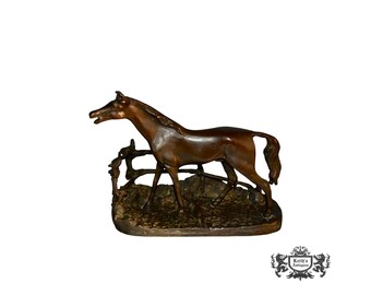 May include: A bronze sculpture of a horse and foal, the horse is standing on its hind legs and the foal is standing on all fours. The sculpture is on a base with a rough texture.