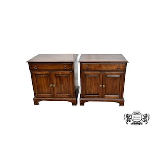 May include: Two matching wooden nightstands with a dark brown finish. Each nightstand has a drawer, two cabinet doors, and brass-colored hardware. The nightstands are on a white background.