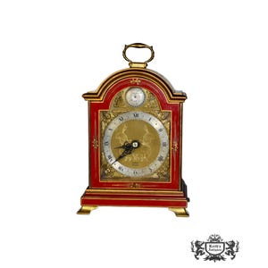 May include: A red and gold antique mantel clock with a Roman numeral clock face and a smaller clock face above it.