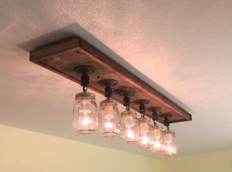 Pu&ograve; includere: Un lampadario rustico per soffitto in legno riciclato con sei luci in barattolo di muratore appese ad esso.